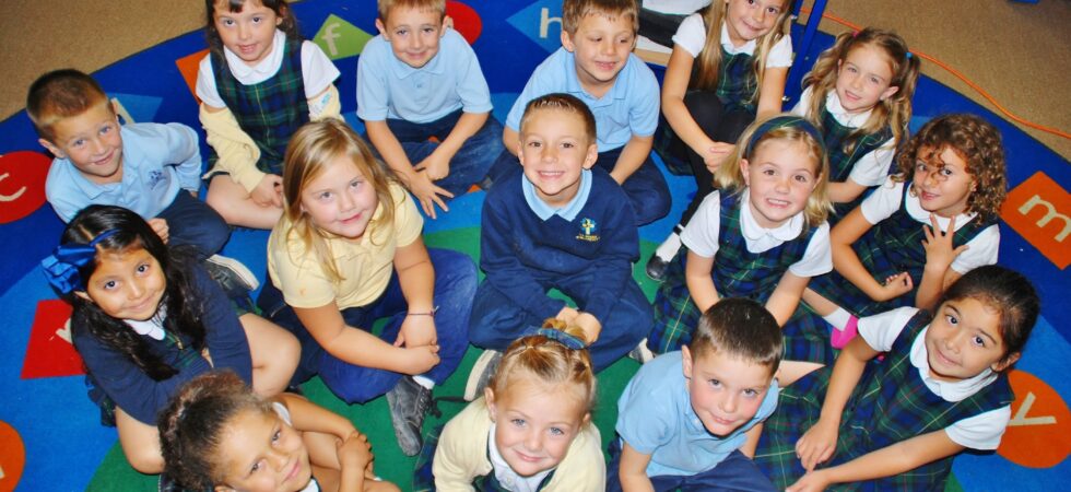children sitting on the rug and smiling during kindergarten class