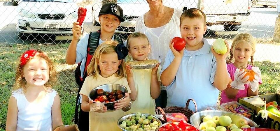 Children holding produce at the gardening sale