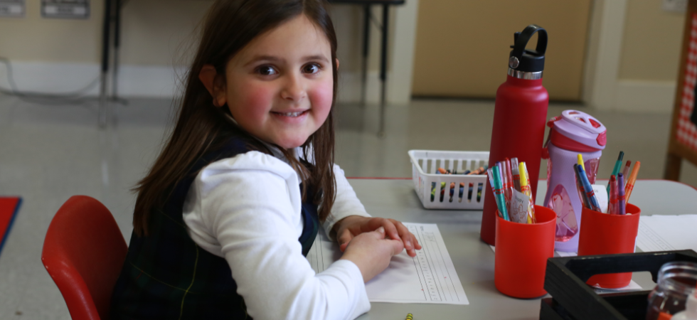 Child sitting at her desk smiling